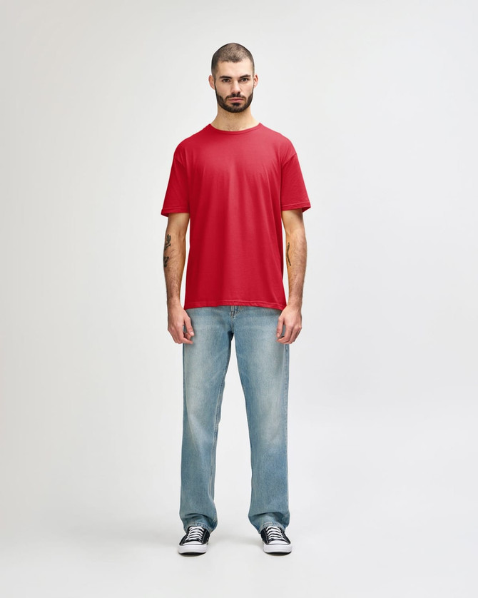 A red Gildan Softstyle adult T-shirt displayed on a male model, paired with light blue jeans. The shirt features a logo.