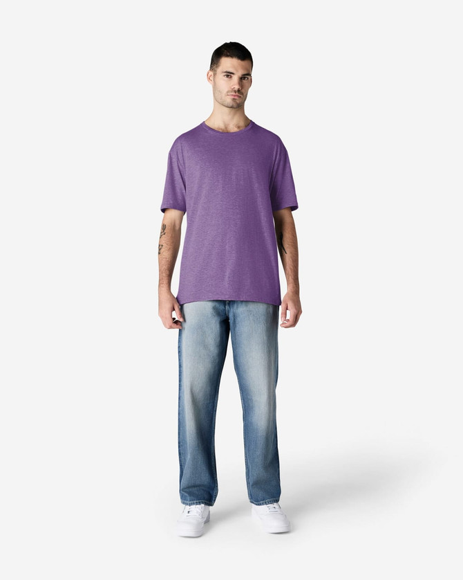 A man wearing a purple Gildan Softstyle adult t-shirt and light blue jeans, standing against a plain background.