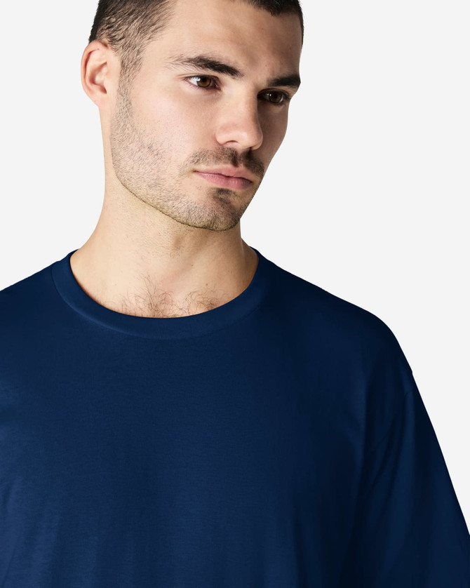 A navy blue softstyle adult t-shirt with a round neckline, worn by a model, featuring a logo.