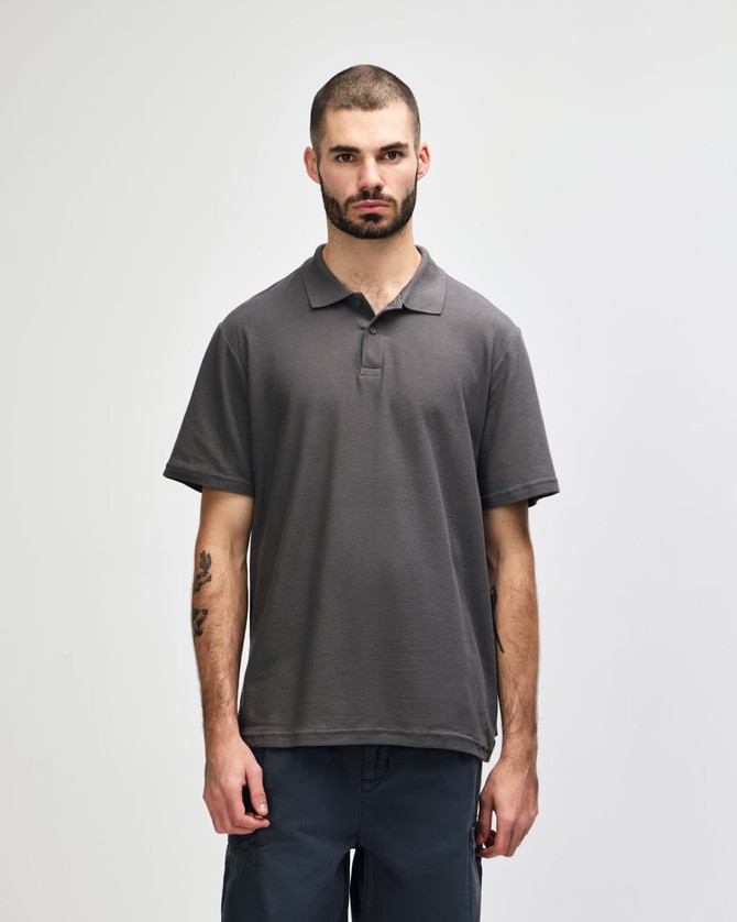 A grey Gildan Softstyle adult double pique polo shirt on a model, featuring a collar and short sleeves.