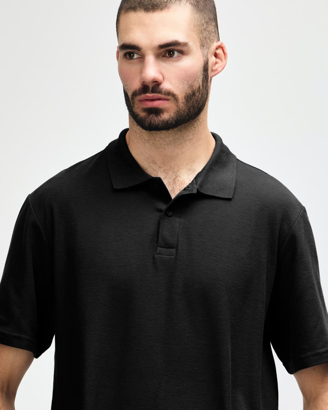 A black Gildan Softstyle adult double pique polo featuring a collared neckline and three buttons. It has a logo on the fabric.