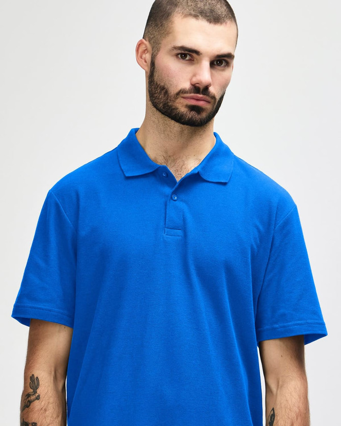 A blue Gildan Softstyle adult double pique polo shirt on a model, featuring a collar and buttons, with a logo.