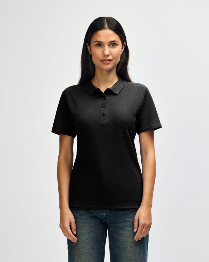 A black Gildan Softstyle ladies' double pique polo shirt with a logo, displayed on a model against a plain background.