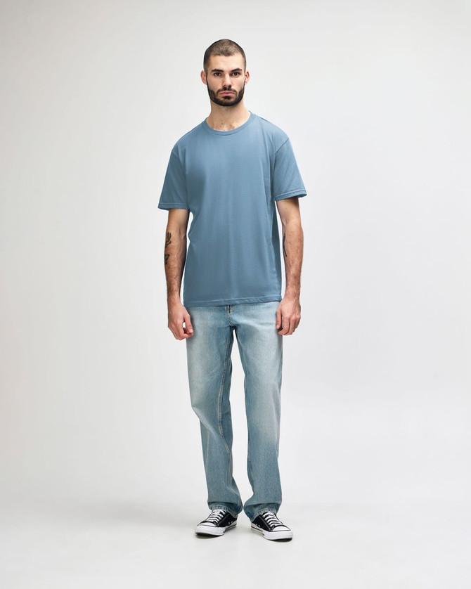 A light blue Gildan Softstyle adult midweight T-shirt displayed on a male model wearing light jeans.