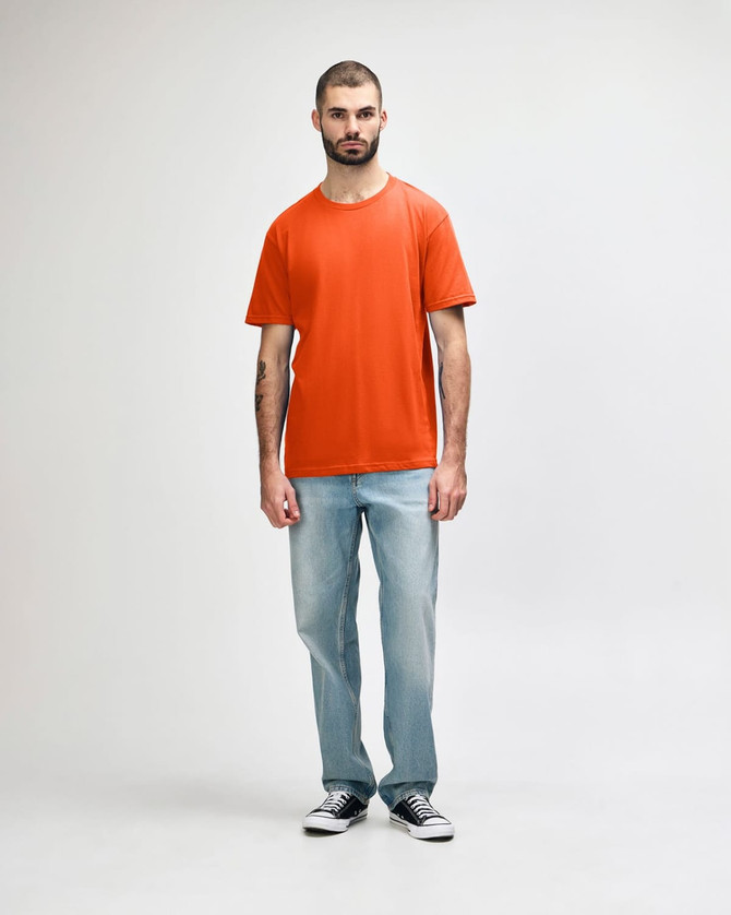 An orange Gildan Softstyle adult midweight T-shirt worn by a model with denim jeans and white shoes.