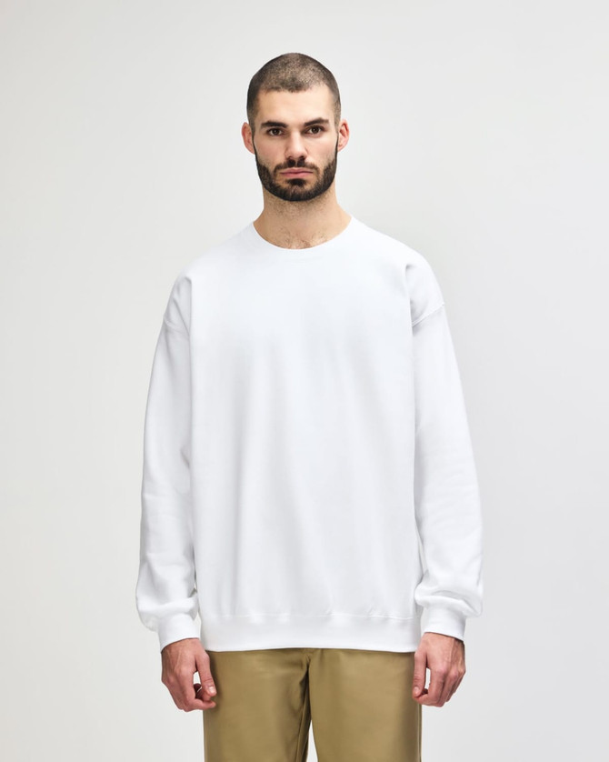 A white Gildan Softstyle adult sweatshirt on a model, featuring long sleeves and a crew neckline.