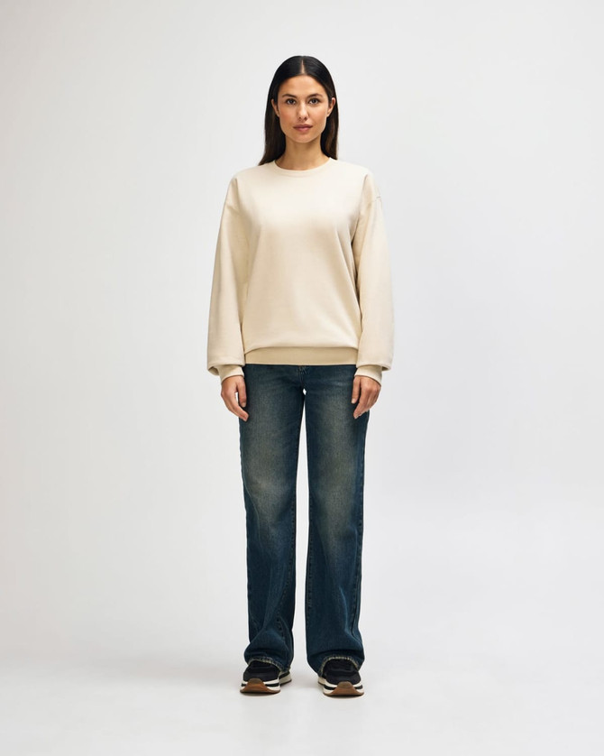 A cream-coloured Gildan Softstyle adult sweatshirt displayed on a model, paired with dark jeans and sneakers.
