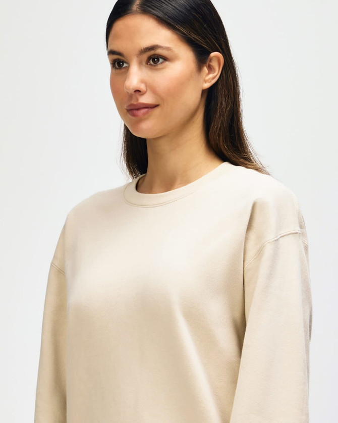 A beige Gildan Softstyle adult sweatshirt displayed on a model, featuring a classic crew neckline and long sleeves.
