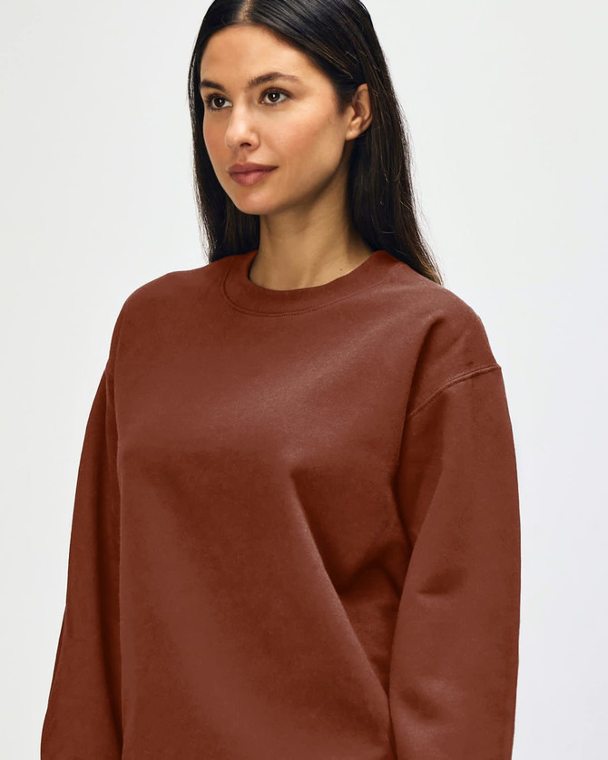 A brown Gildan Softstyle adult sweatshirt worn by a model, featuring a simple design and a logo.