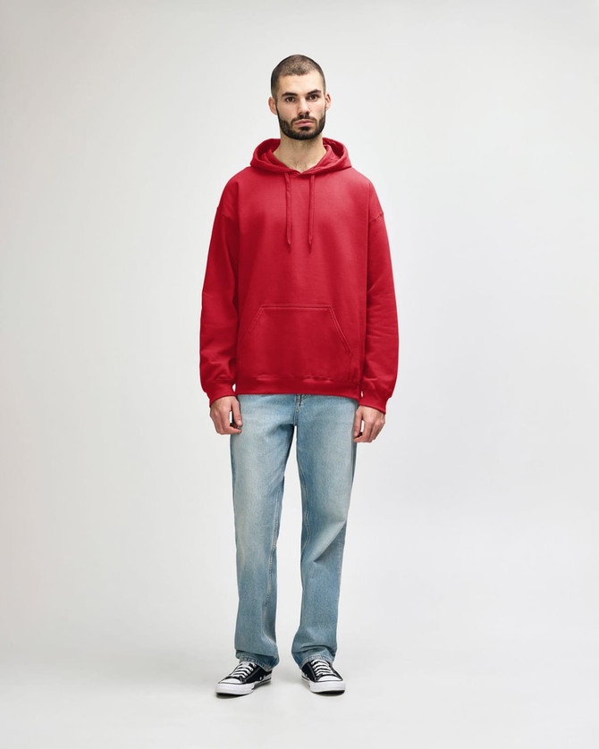 A red Gildan Softstyle adult hooded sweatshirt worn by a model, paired with blue jeans and white shoes.