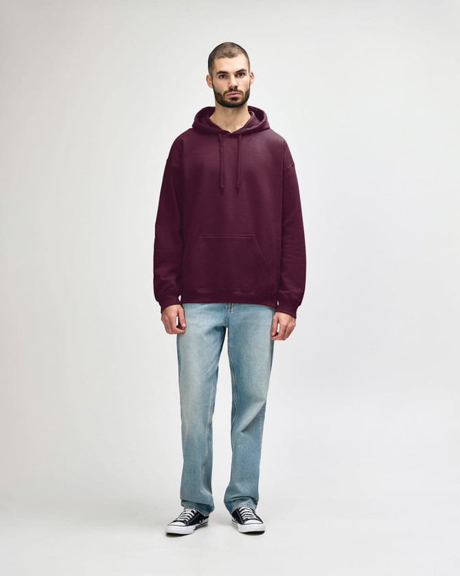 A woman is wearing a burgundy hooded sweatshirt paired with blue jeans and white sneakers. The sweatshirt has a logo.