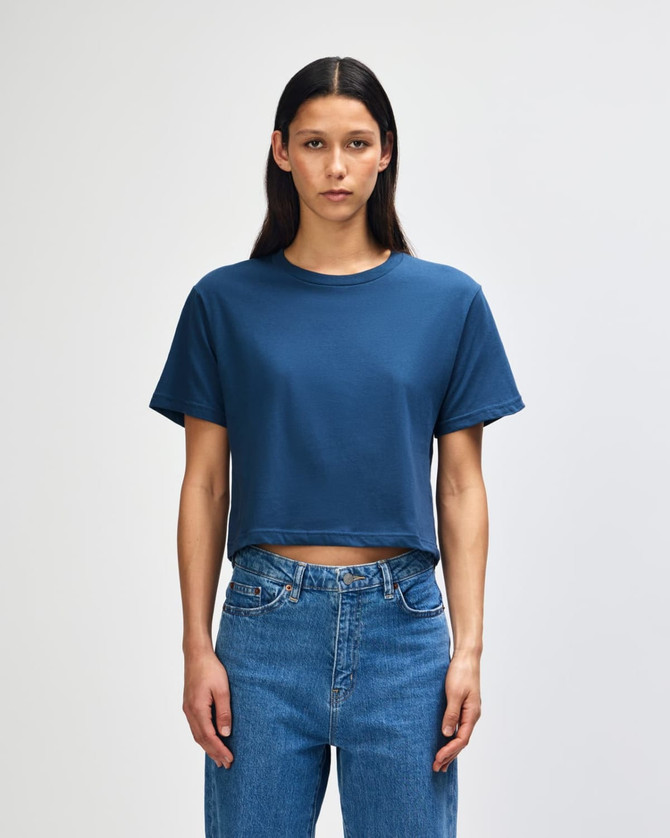 A navy women's fine jersey boxy T-shirt featured on a model, paired with light blue jeans. The shirt has a logo.