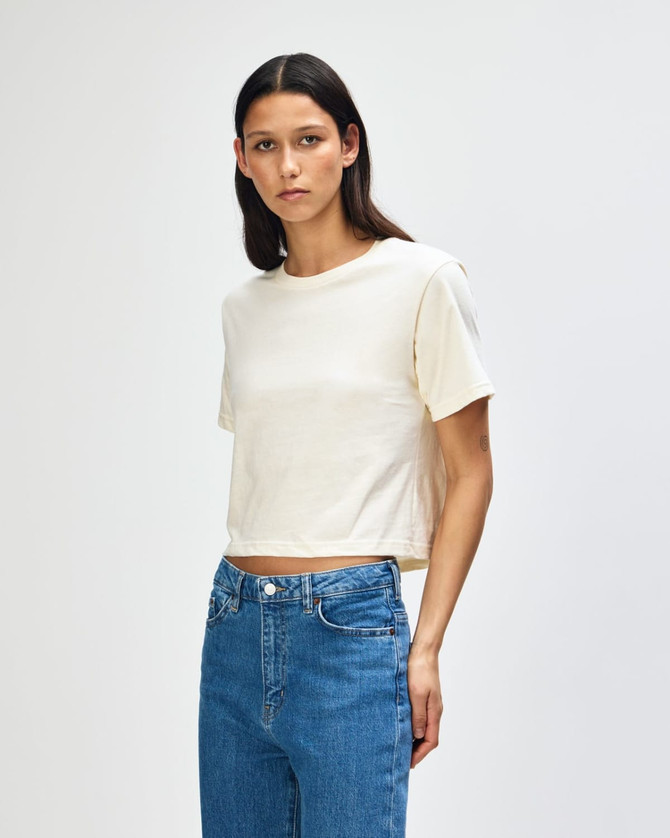 A women's fine jersey boxy t-shirt in cream, paired with light blue jeans, featuring a branding logo.