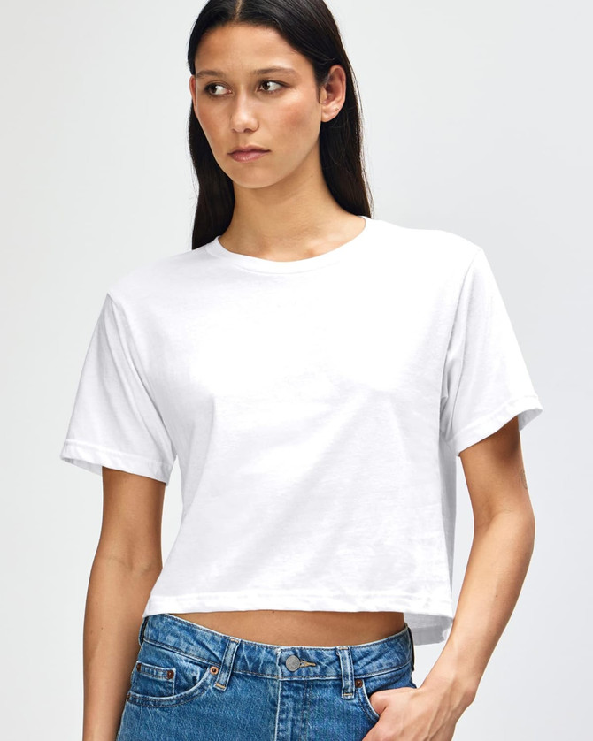 A white women's fine jersey boxy t-shirt displayed on a model, featuring a minimalistic design and an attached logo.