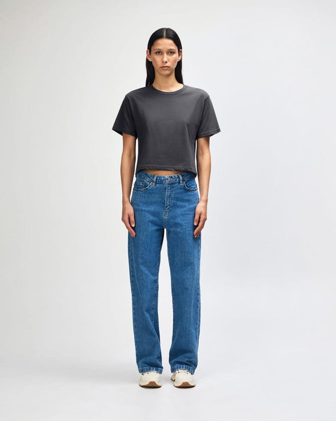 A woman wearing a grey boxy t-shirt and light blue cargo jeans, paired with black and white sneakers.