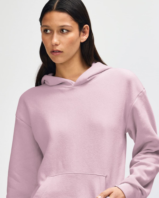 A unisex hooded sweatshirt in soft pink, featuring a front pocket and a branding logo.