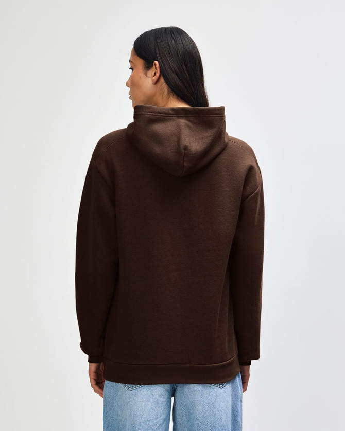 A unisex hooded sweatshirt in brown, featuring a spacious hood and a relaxed fit, with branding on the garment.
