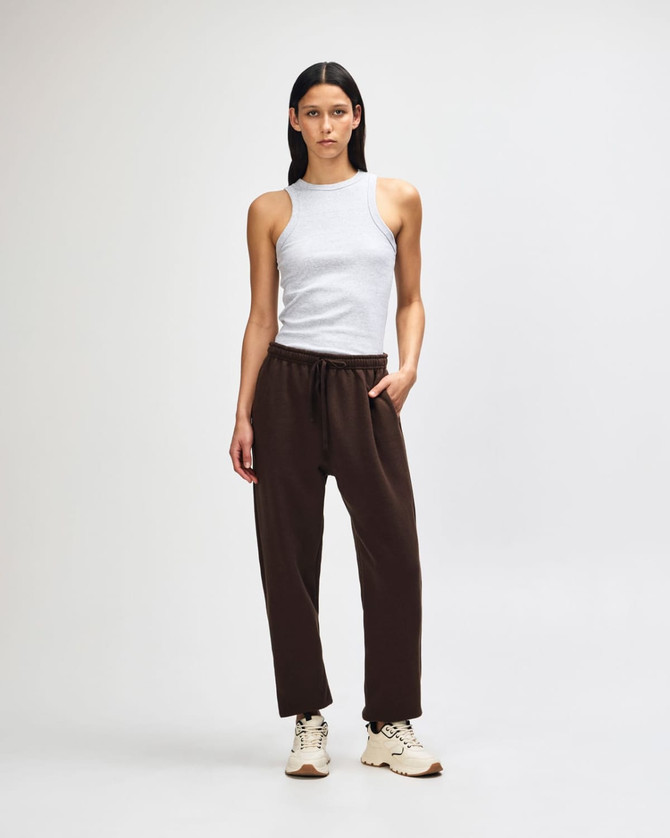 Unisex sweatpants in brown with an elastic waistband; styled with a matching brown hoodie. Features a branding logo.