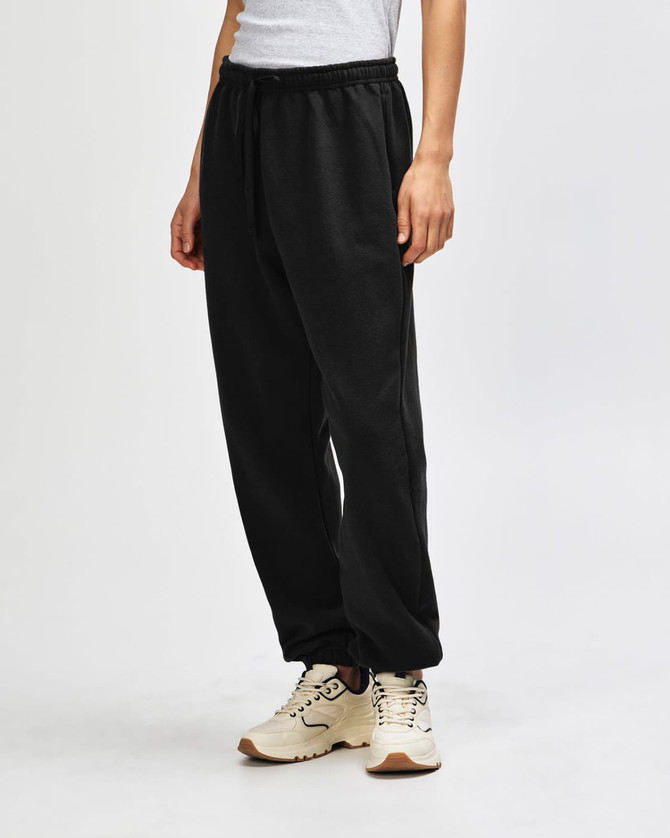 Unisex sweatpants in black with a drawstring waist, showcased on a model standing sideways.