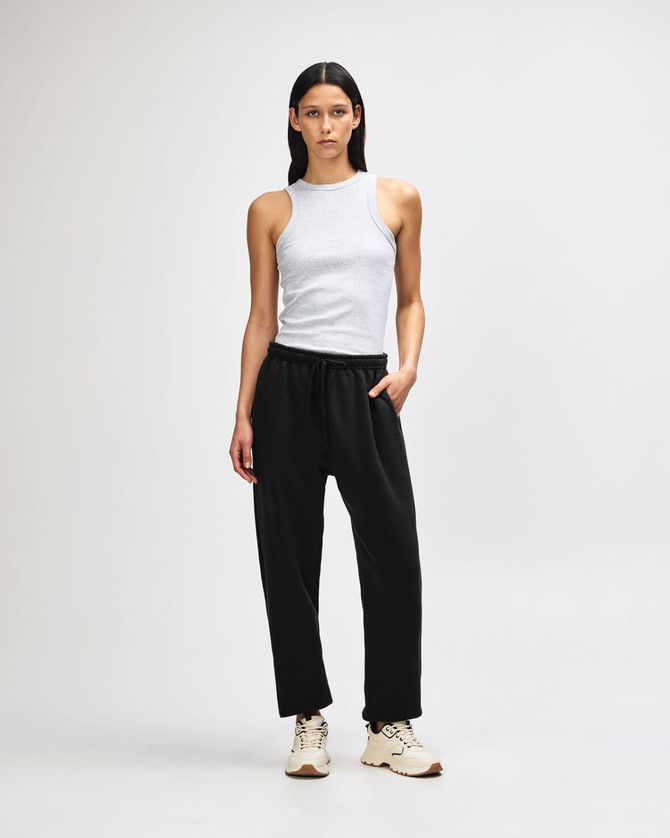 Unisex sweatpants in black, featuring a loose fit and elastic waistband. The model pairs them with a matching hoodie.