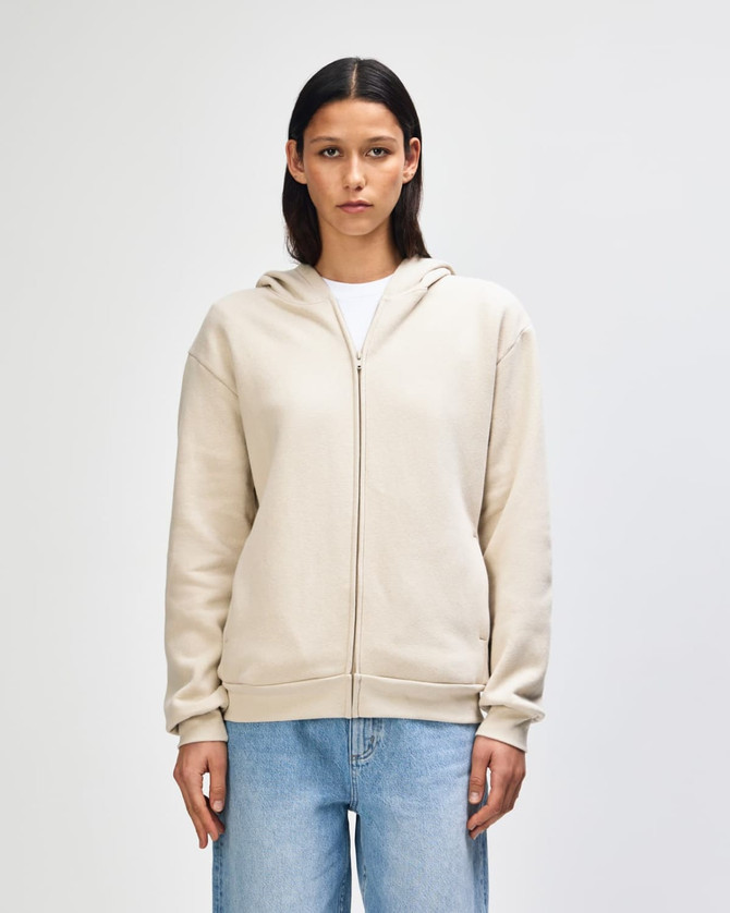 A unisex full zip hooded sweatshirt in a light beige colour with a hood and front zip, featuring a logo.