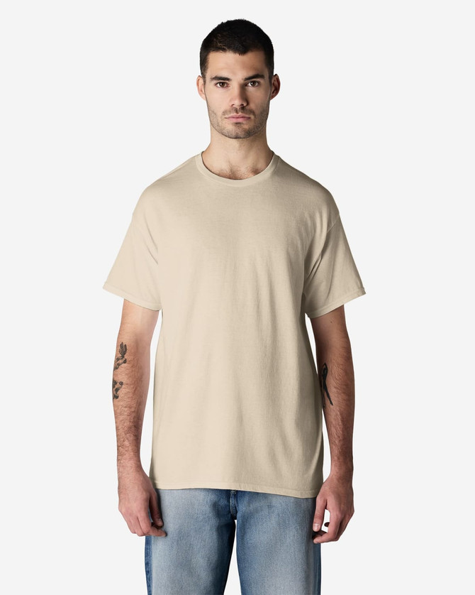 A light beige Gildan cotton t-shirt displayed on a model, featuring a simple design and a logo.