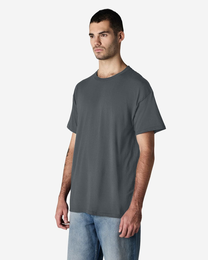 A grey Gildan Light Cotton T-Shirt displayed on a model wearing blue jeans, featuring a logo on the shirt.