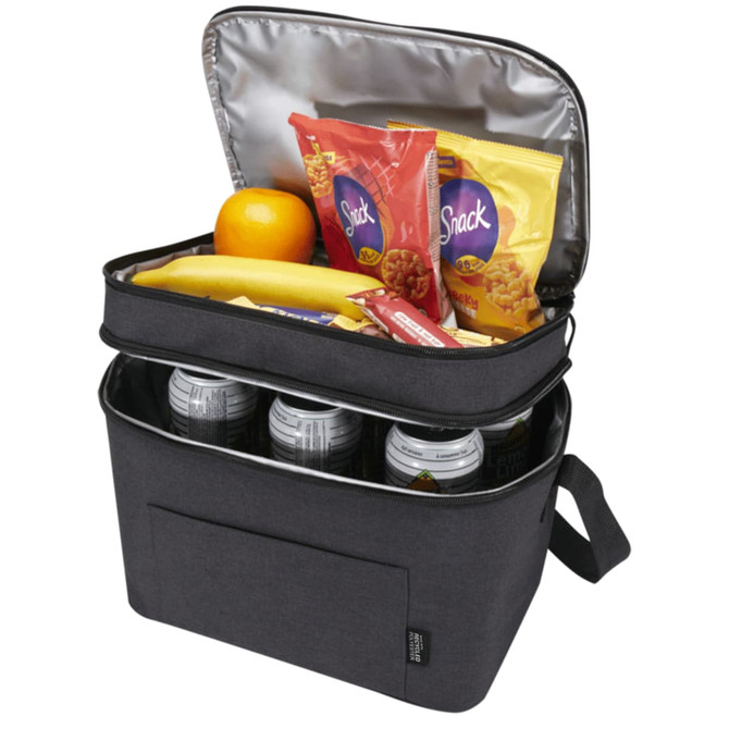 A double compartment cooler bag in charcoal grey, containing snacks, fruit, and drink cans. It has a logo and an unzipped lid.