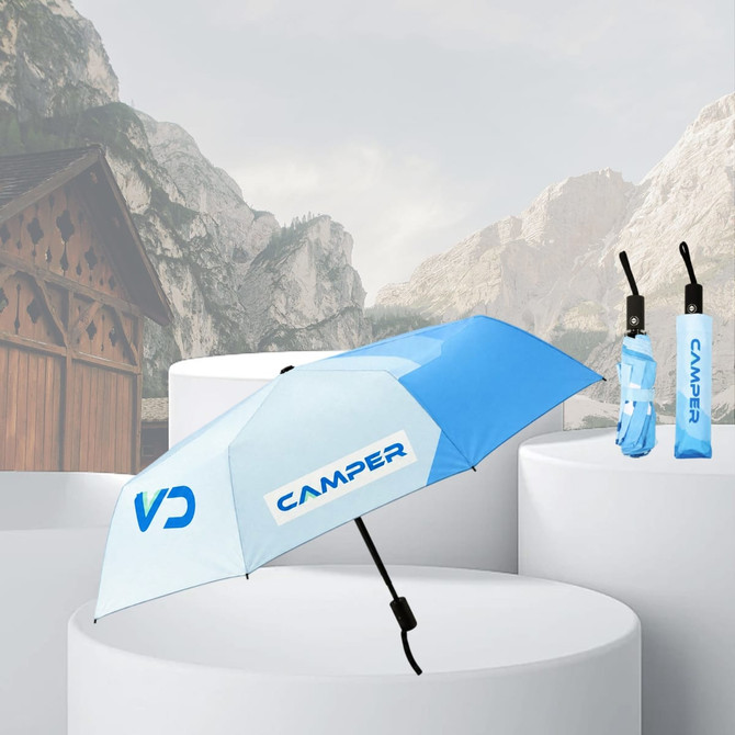 A blue and white anti-rebound folding umbrella with a logo, displayed on a pedestal with a backdrop of mountains.