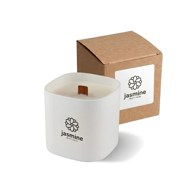 A square, white glass candle with a wooden wick, accompanied by a brown cardboard box. Branding is visible on the box.