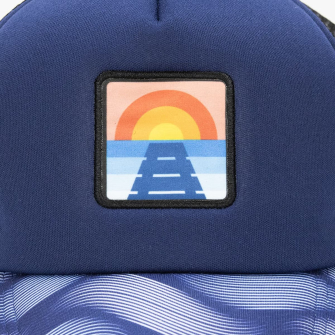 A trucker cap featuring a navy blue design with a full colour patch depicting a sunset over a pathway.