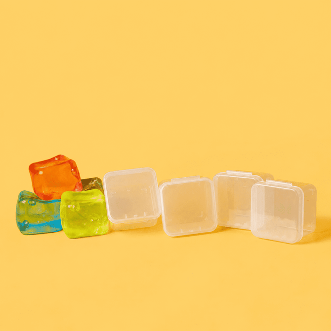 A row of clear plastic jelly cube sensory toys in orange, blue, and green against a yellow background.
