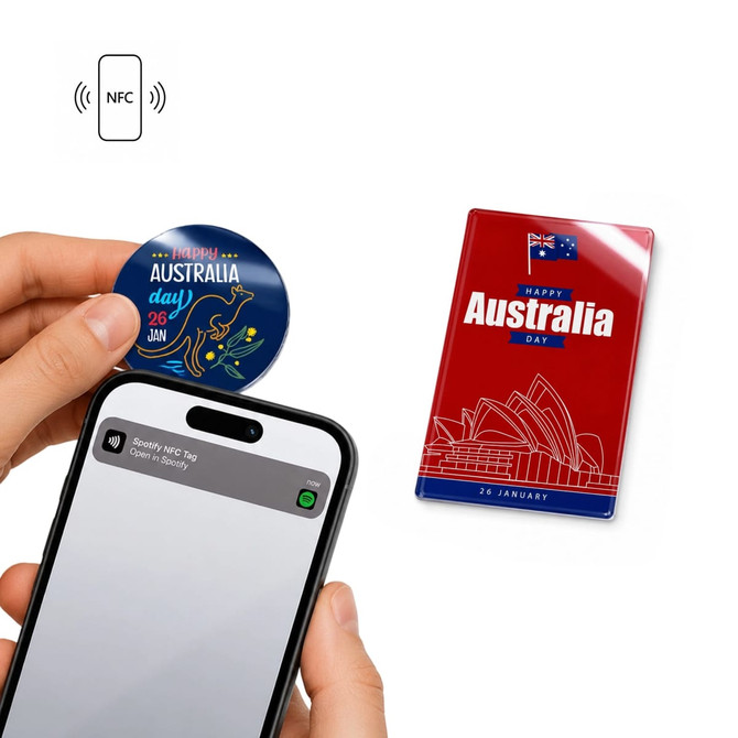 A hand holds a phone near two NFC acrylic fridge magnets, one featuring a depiction of Australia and the other Australia Day design.