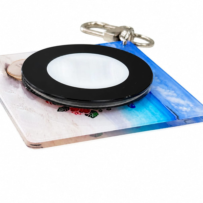 A black and clear NFC acrylic spinning keychain featuring a colourful background design.