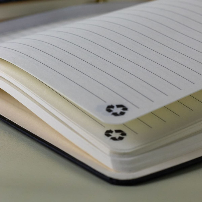 An A5 notebook with lined pages, featuring a black cover and a recycling symbol on the tabs.