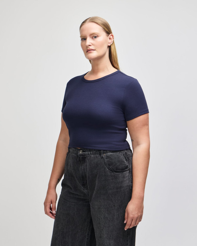 A navy blue crop fitted t-shirt for women, paired with high-waisted jeans, featuring a branding logo.