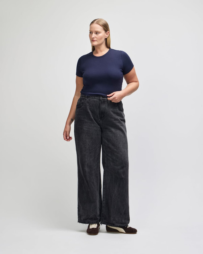 A fitted navy blue women's crop t-shirt paired with high-waisted black wide-leg jeans.
