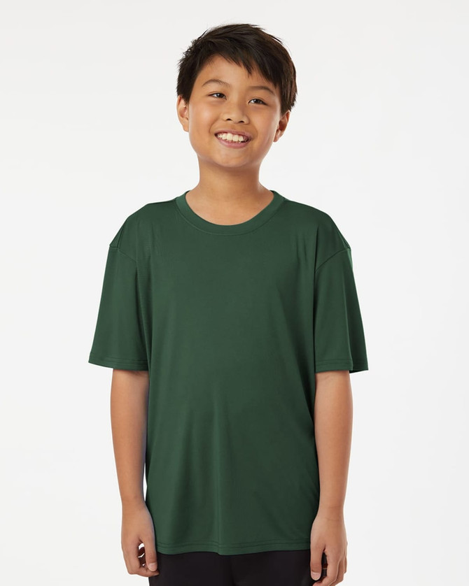 A boy wearing a green short-sleeved performance polo shirt with a relaxed fit and a simple design.