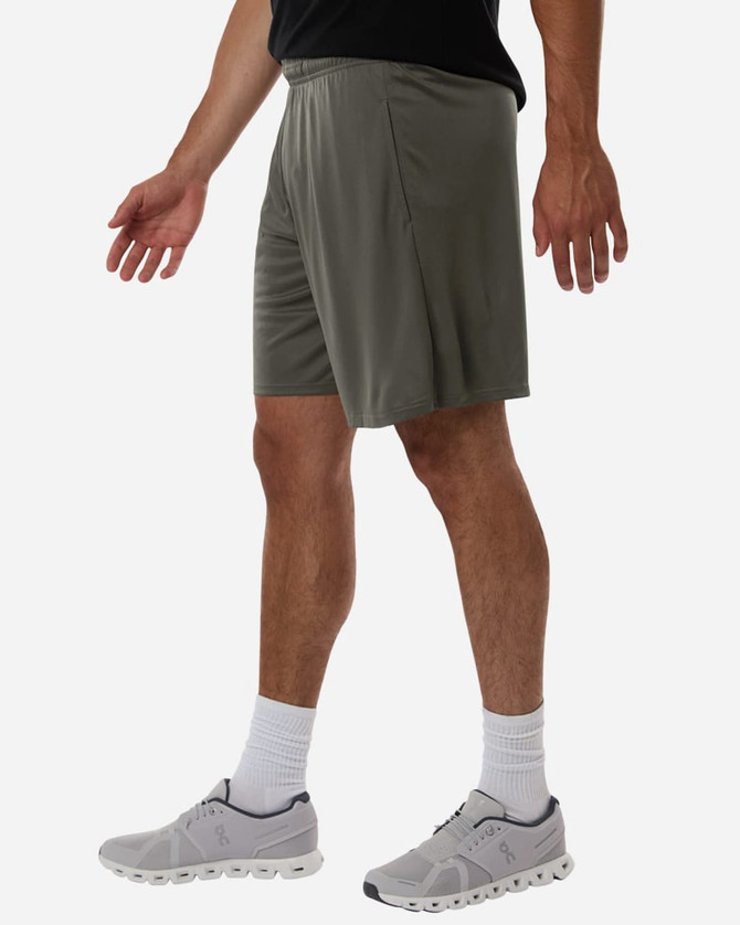 A man wearing grey athletic shorts and grey sneakers, standing with hands at his sides against a neutral background.