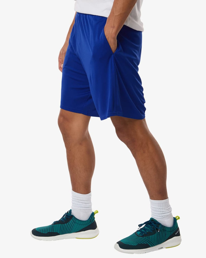 A pair of blue athletic shorts featuring side pockets, worn with green and black sports shoes.