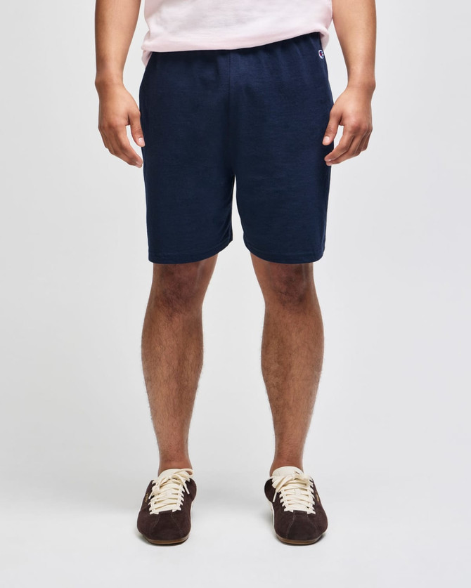 Navy cotton gym shorts with an elastic waistband and a logo, modelled by a person standing upright.