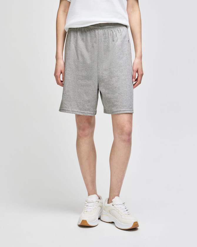 Grey cotton gym shorts with an elastic waistband, worn by a person standing in white shoes. Features a logo.