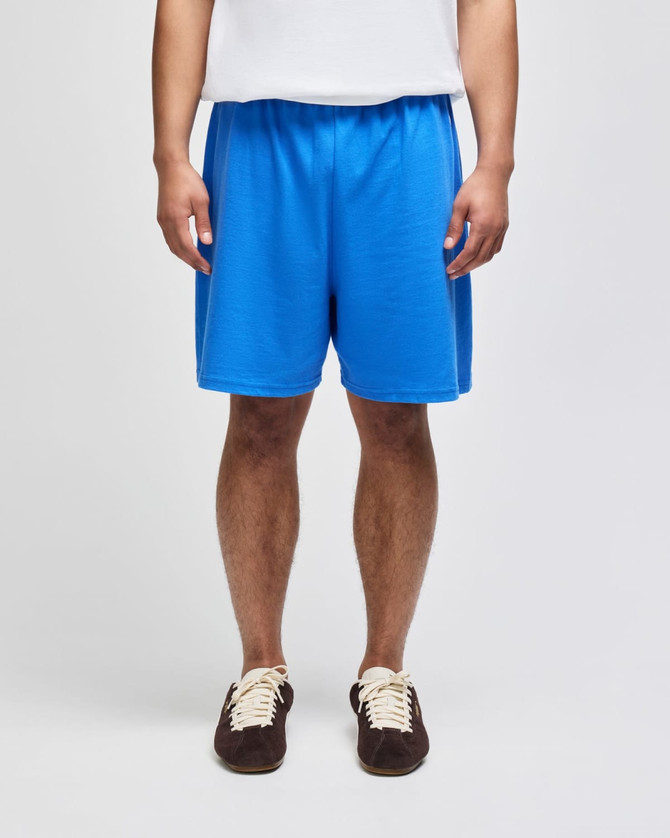 Bright blue cotton gym shorts with an elastic waistband, modelled by a person standing upright.