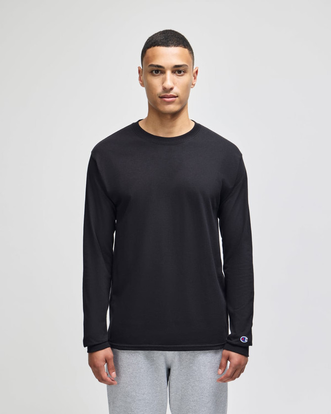A black long-sleeve t-shirt with a logo, modelled by a person, paired with grey trousers.
