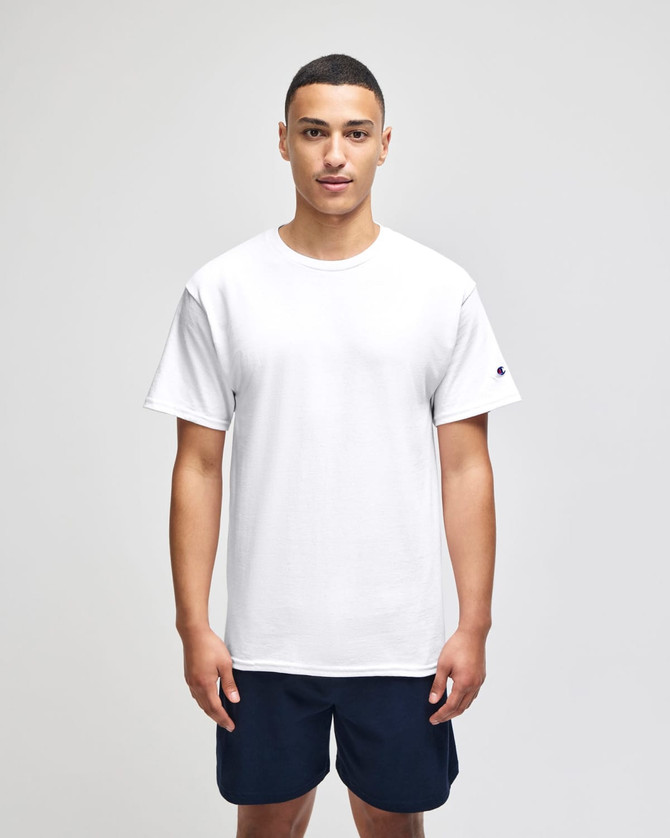 A man wearing a white short sleeve t-shirt and navy shorts, featuring a logo on the sleeve.