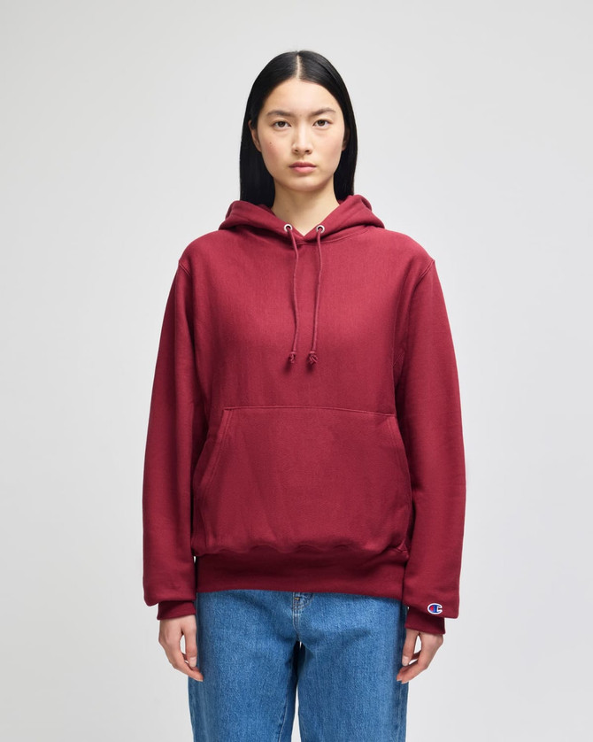 A maroon pullover hooded sweatshirt with a front pocket and a logo on the sleeve. Suitable for casual wear.