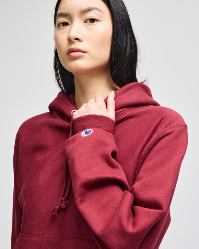 A burgundy hooded sweatshirt with a front pouch pocket and a logo on the sleeve.
