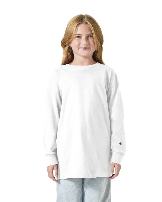 A white long sleeve T-shirt for youth, featuring a logo on the sleeve. The model is smiling and wearing casual jeans.