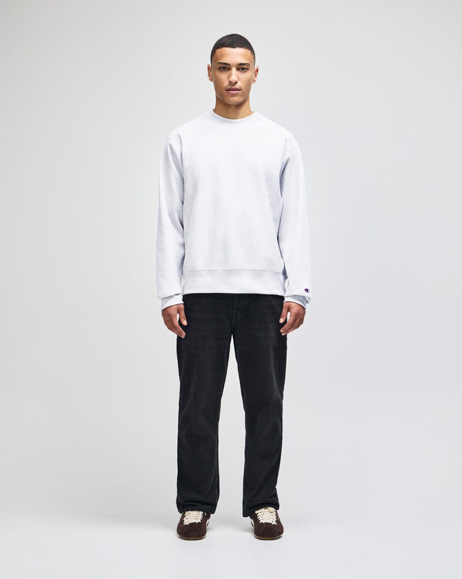 A grey Champion Reverse Weave® adult crew sweatshirt worn by a model with dark trousers and shoes.