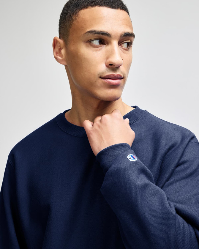 A navy blue Champion Reverse Weave® adult crew sweatshirt with a logo on the sleeve.